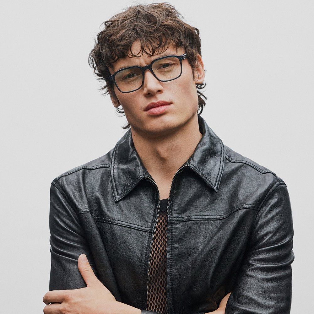 Portrait d'un homme en veste de cuir, portant des montures Prodesign carrées, sur fond clair.