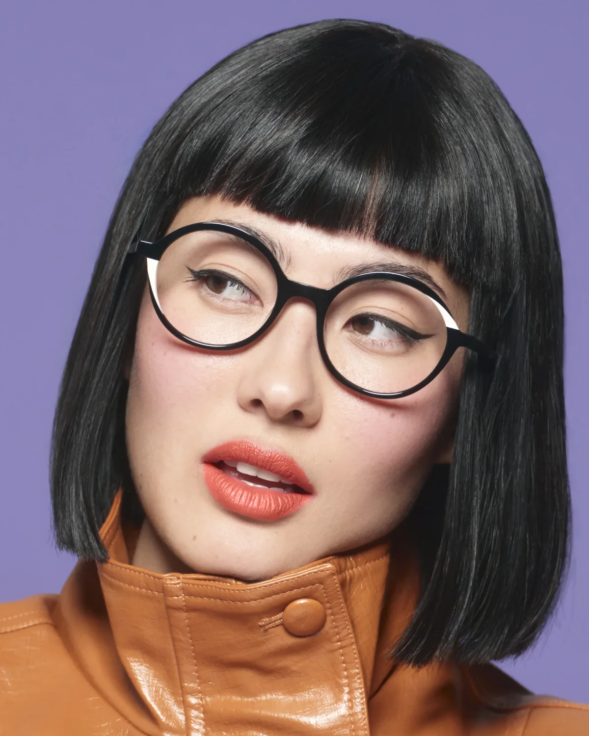 Portrait d'une femme portant des montures WOOW noires rondes, sur fond violet.